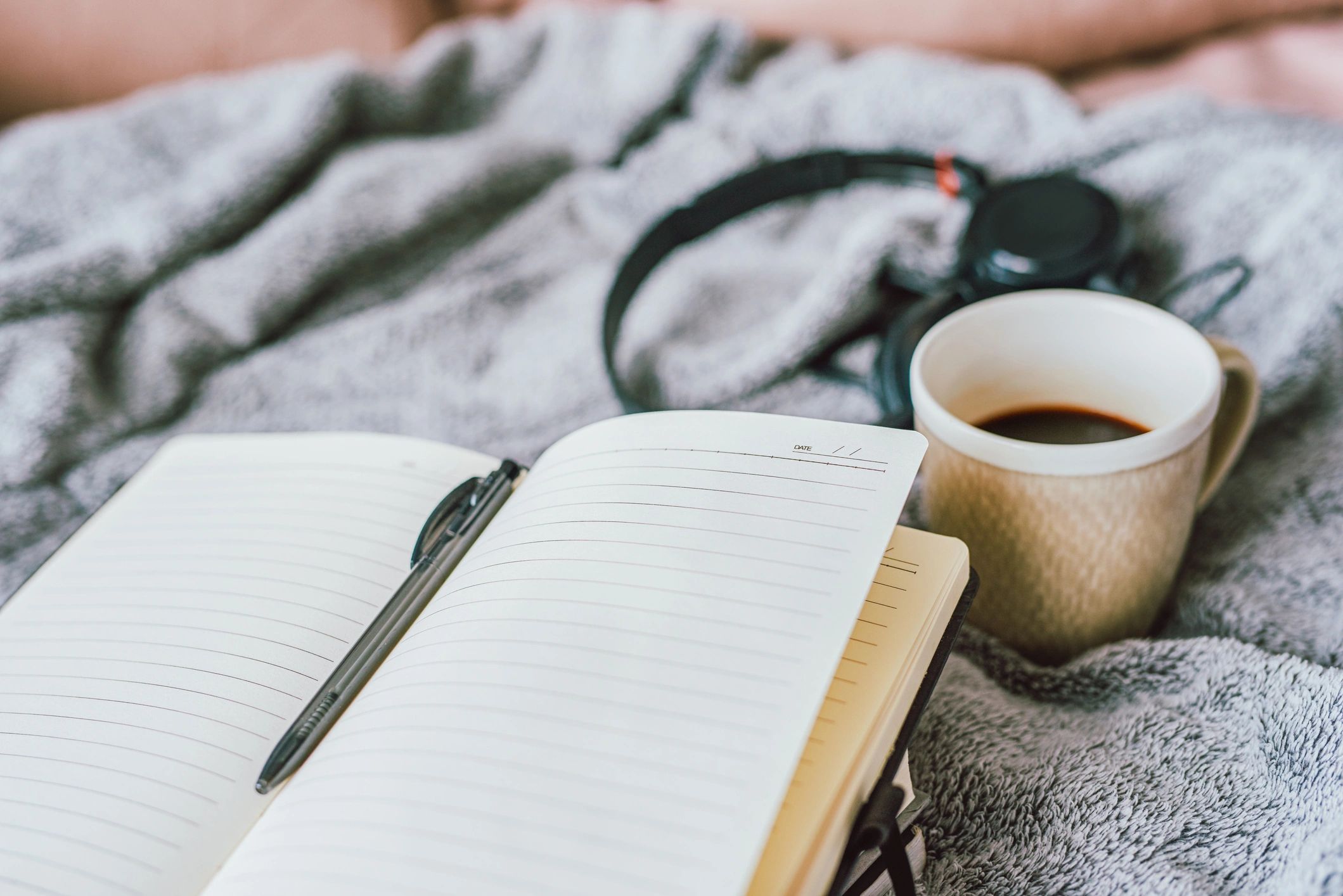 Notebook on a bed with coffee and headphones